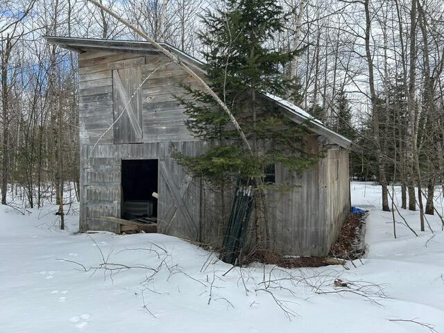 snow covered structure featuring a barn, a garage, and an outdoor structure