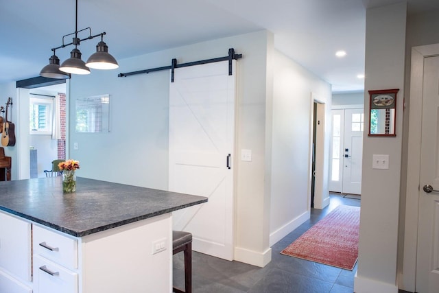 kitchen featuring a barn door, pendant lighting, a breakfast bar area, and white cabinets