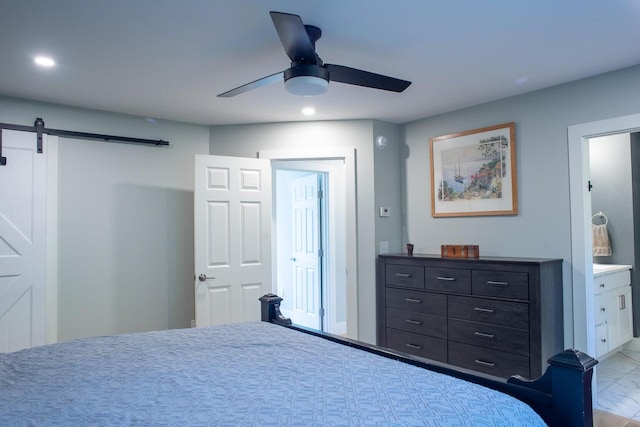 bedroom featuring ceiling fan, a barn door, and ensuite bath