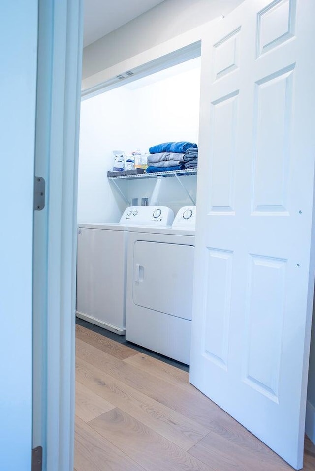 laundry area with washer and clothes dryer and light hardwood / wood-style flooring