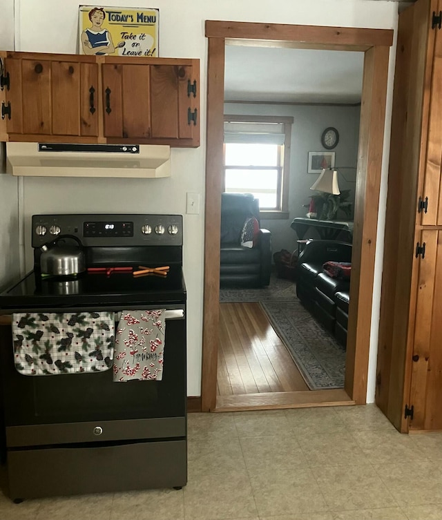 kitchen with electric range, brown cabinetry, and under cabinet range hood