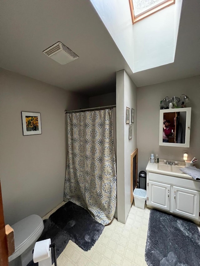 full bath featuring toilet, a skylight, vanity, visible vents, and tile patterned floors