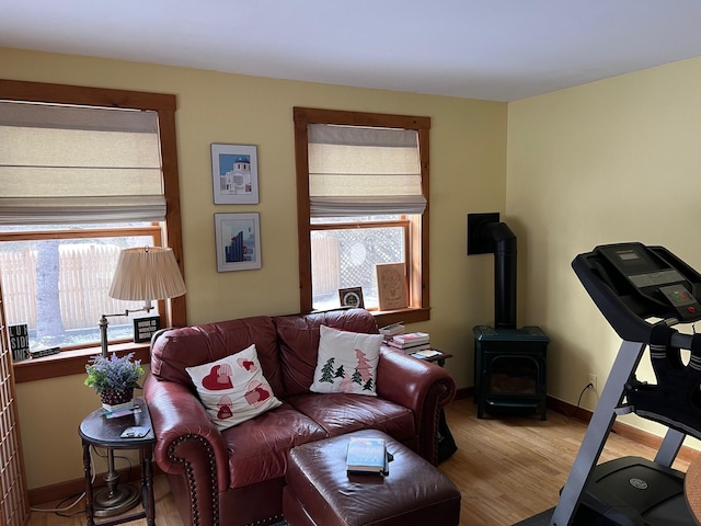 living room with wood finished floors, a wood stove, and baseboards