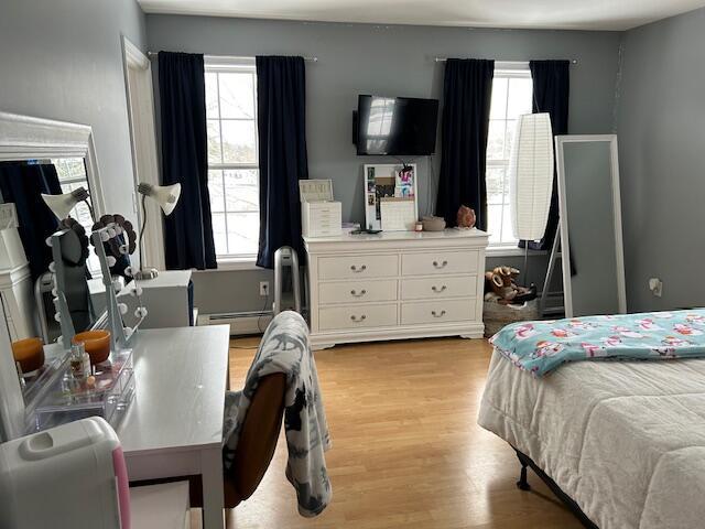 bedroom with a baseboard radiator and light hardwood / wood-style flooring