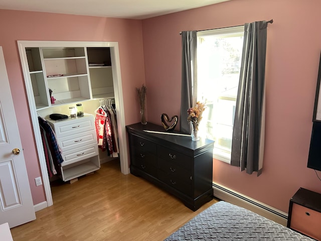 bedroom featuring light hardwood / wood-style flooring, a baseboard radiator, and a closet