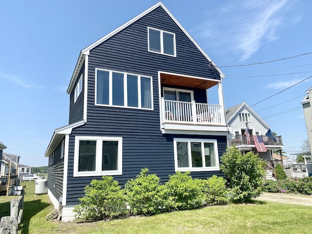 view of home's exterior featuring a balcony and a yard