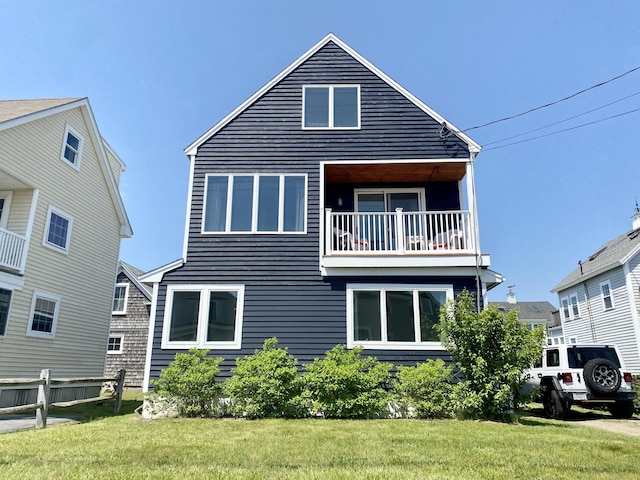 rear view of property featuring a balcony and a yard