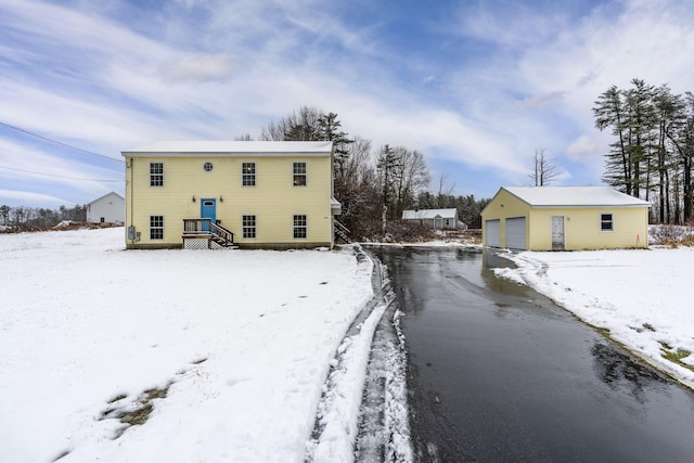 snow covered property featuring a garage and an outdoor structure