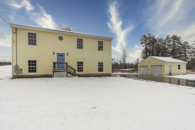 snow covered house with a garage and an outdoor structure