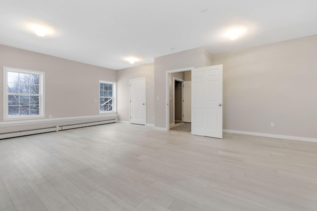 empty room with a baseboard heating unit and light hardwood / wood-style floors