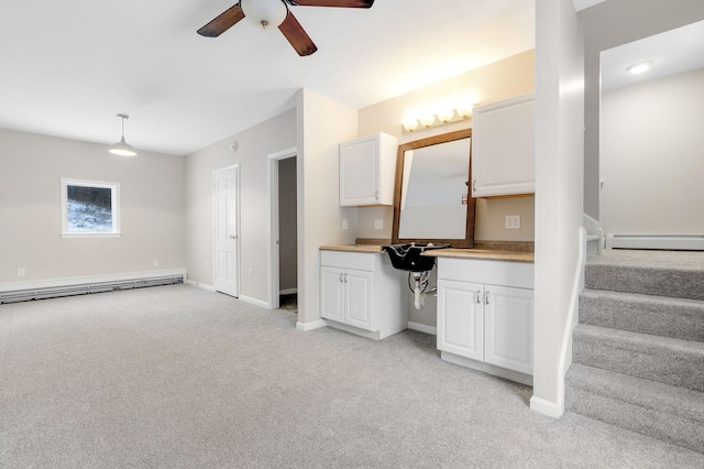 kitchen featuring built in desk, pendant lighting, white cabinetry, a baseboard heating unit, and light carpet