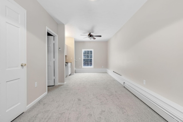 unfurnished room with light carpet, a baseboard heating unit, and ceiling fan