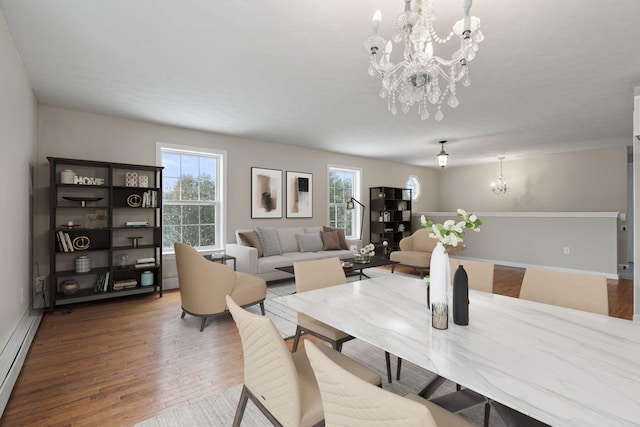 dining room with an inviting chandelier, baseboard heating, and hardwood / wood-style flooring