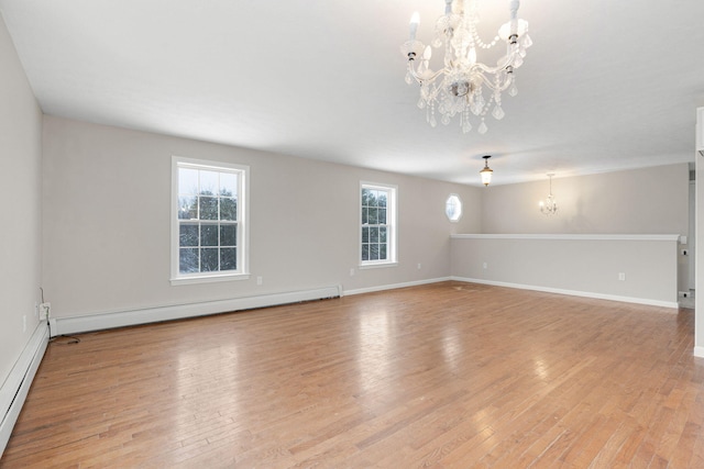 unfurnished room with a baseboard heating unit, light hardwood / wood-style floors, and a notable chandelier