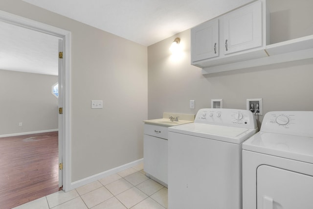 clothes washing area featuring cabinets, sink, light tile patterned floors, and independent washer and dryer