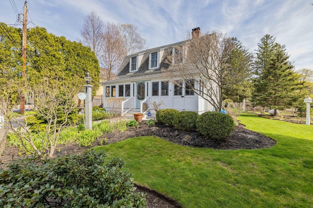 view of front of house featuring a chimney and a front yard