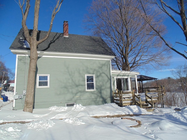 snow covered house featuring a chimney