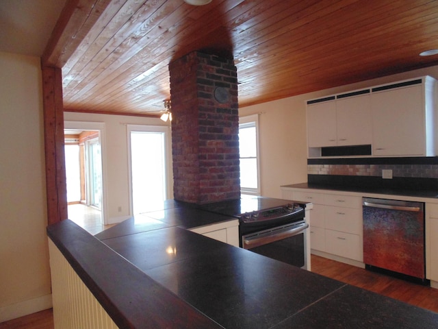 kitchen with appliances with stainless steel finishes, dark countertops, light wood-style floors, and decorative backsplash