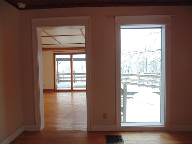 doorway with light wood-style flooring, visible vents, and baseboards