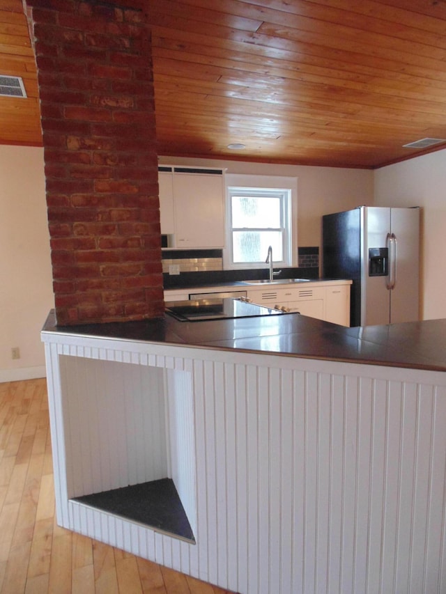 kitchen featuring visible vents, stainless steel fridge with ice dispenser, dark countertops, wooden ceiling, and a sink