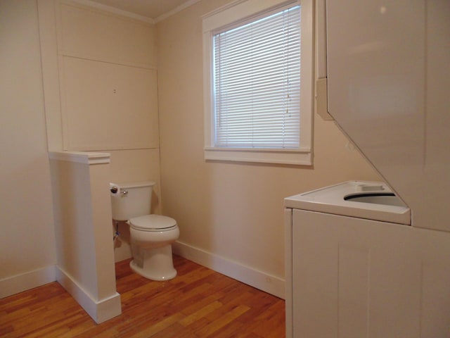 half bath featuring crown molding, wood finished floors, toilet, and baseboards