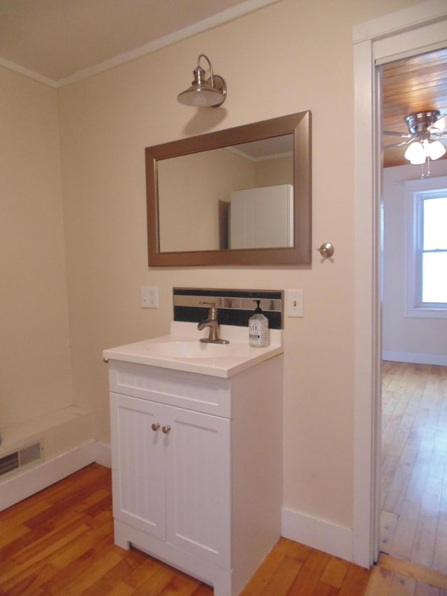 bathroom featuring visible vents, ornamental molding, vanity, wood finished floors, and baseboards