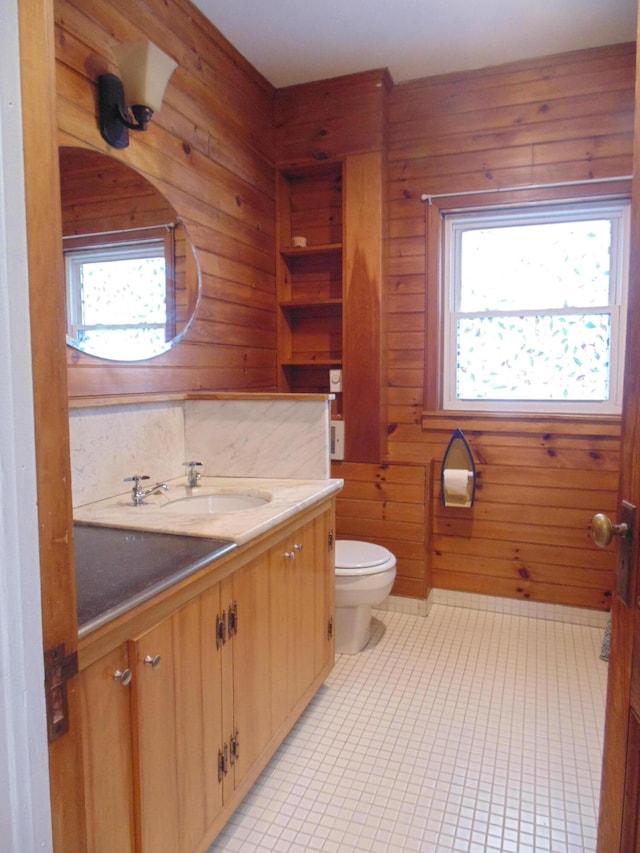 bathroom with wood walls, vanity, toilet, and tile patterned floors