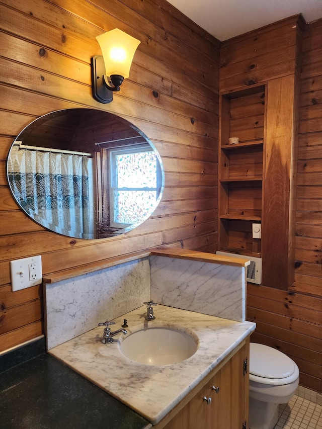 full bath with wood walls, vanity, toilet, and tile patterned floors