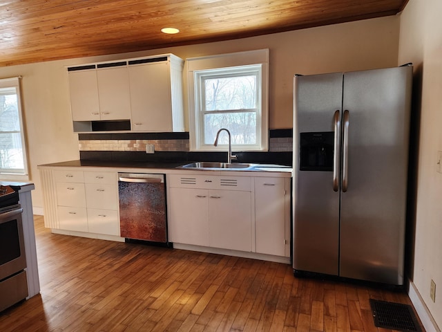 kitchen with appliances with stainless steel finishes, a sink, wood ceiling, and decorative backsplash