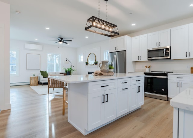 kitchen featuring decorative light fixtures, a kitchen island, white cabinets, and appliances with stainless steel finishes