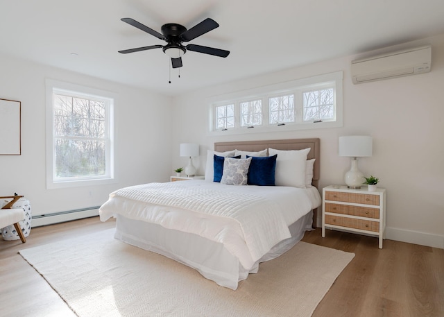 bedroom featuring hardwood / wood-style flooring, a baseboard radiator, a wall mounted AC, and multiple windows