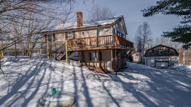 snow covered rear of property featuring a wooden deck and a storage shed