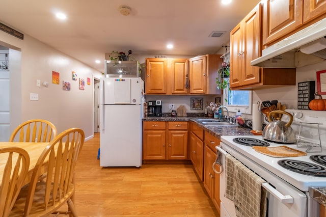 kitchen featuring dark stone countertops, sink, white appliances, and light wood-type flooring