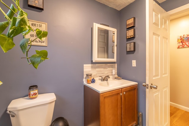 bathroom featuring vanity, wood-type flooring, backsplash, and toilet