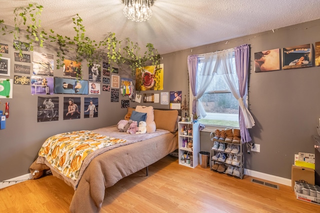 bedroom featuring an inviting chandelier, hardwood / wood-style floors, and a textured ceiling