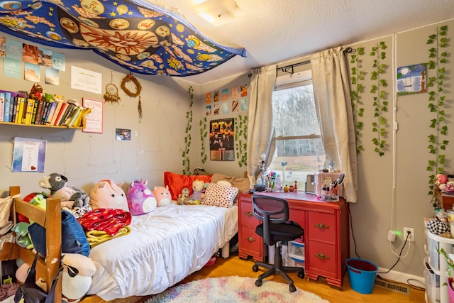 bedroom with light hardwood / wood-style flooring and a textured ceiling