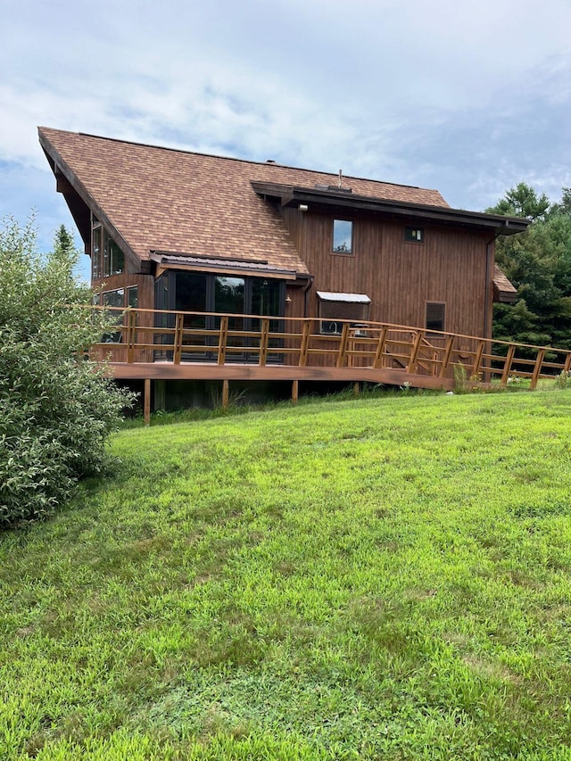 rear view of house featuring a wooden deck and a lawn