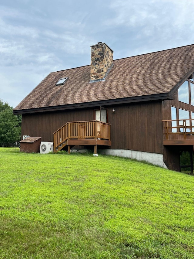 back of property featuring a deck and a lawn