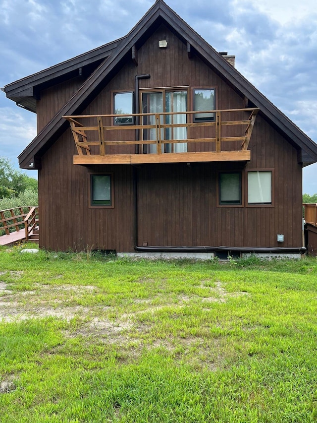 back of house with a balcony and a yard