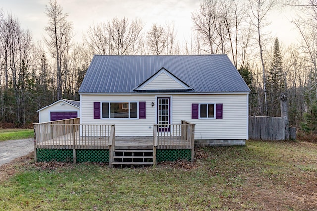 view of front of house featuring a garage, an outdoor structure, a deck, and a lawn