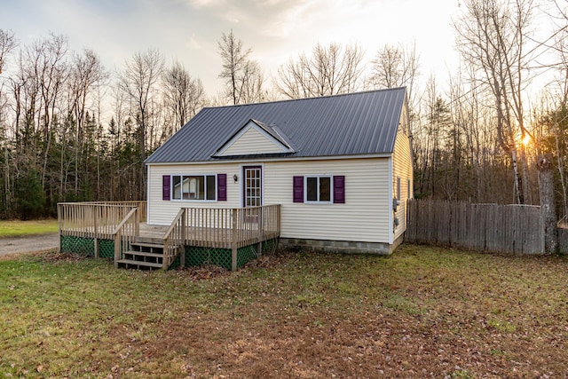 back house at dusk featuring a lawn and a deck