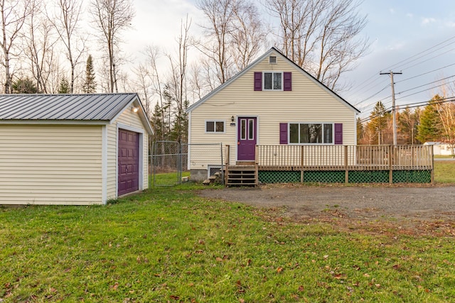 rear view of property with a garage, a yard, an outbuilding, and a deck