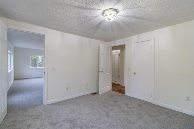 spare room featuring light carpet and a textured ceiling