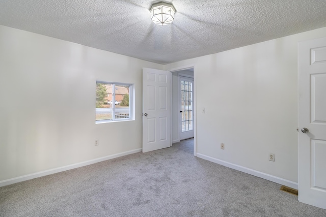 unfurnished room featuring light carpet and a textured ceiling