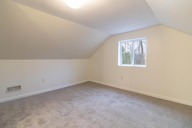 additional living space with vaulted ceiling and carpet flooring