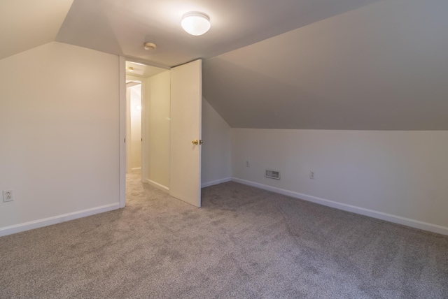 bonus room with lofted ceiling and light colored carpet