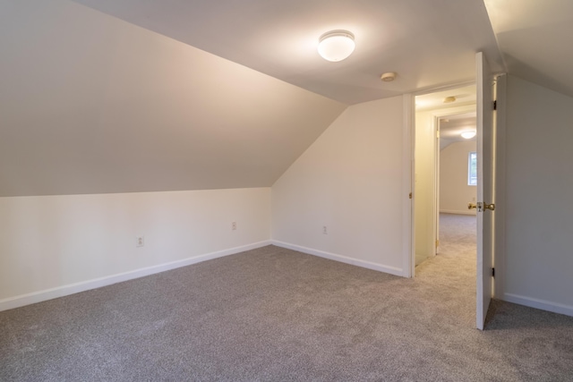 additional living space featuring lofted ceiling and carpet flooring