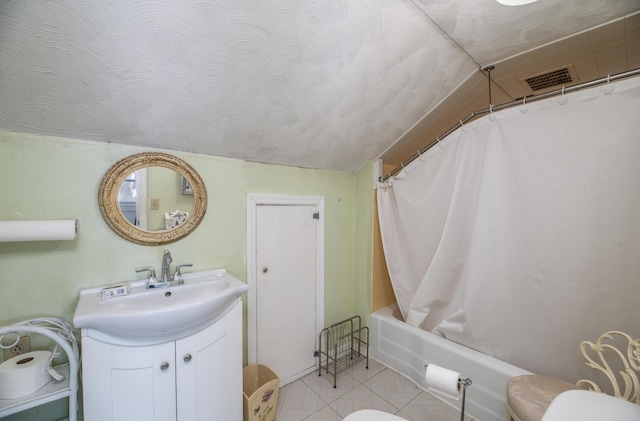 full bathroom with tile patterned flooring, toilet, a textured ceiling, shower / bath combo with shower curtain, and vanity