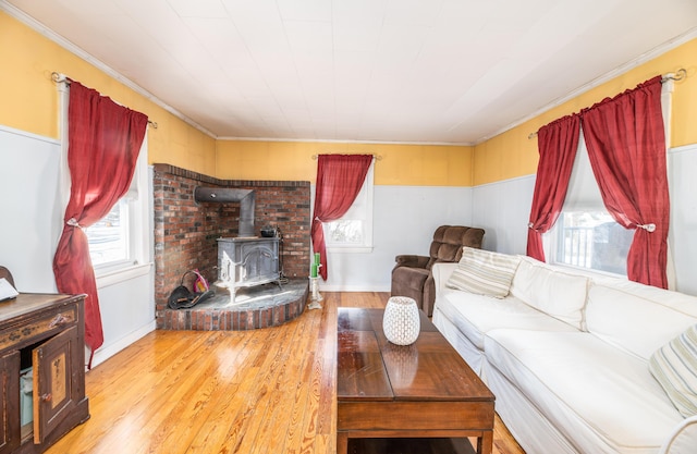 living room featuring light hardwood / wood-style floors, crown molding, and a wood stove