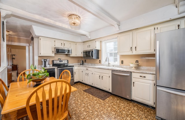 kitchen featuring sink, white cabinetry, stainless steel appliances, and beam ceiling